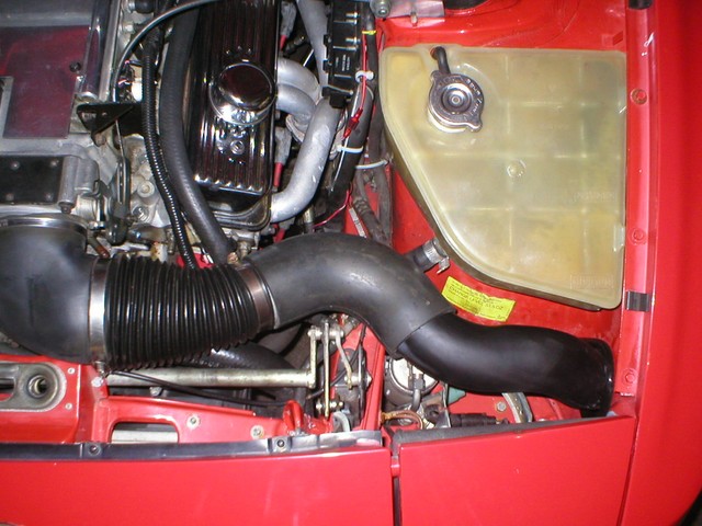 Cool air intake, our first attempt. This is a difficult thing to accomplish, as there are many things in the way. First off, the LT1 has an oval throttle body of an odd sise. The rubber elbow at the left adapts us from the Chevy oval to 4